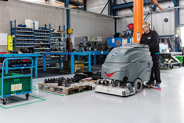 Robotstofzuiger in een moderne fabriekshal, schoonmaakrobot voor industriële reiniging, ICE Cobotics, automatisering, efficiënte schoonmaak, productieomgeving, geavanceerde technologie, industriële robot, slimme schoonmaakoplossingen.